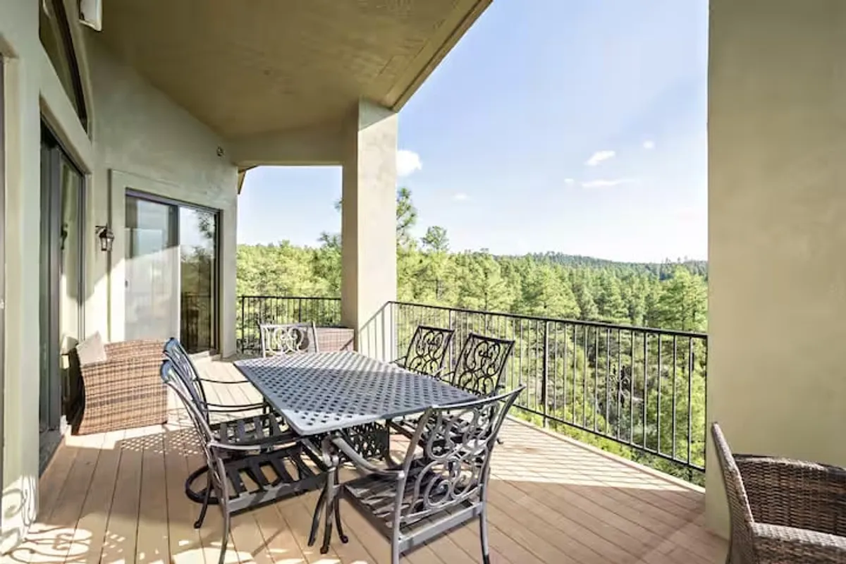 An outdoor dining area framed by wrought iron railings and lush greenery, suggesting a tranquil space for al fresco breakfasts, sunset dinners, or stargazing. The space feels welcoming for social gatherings and relaxation after a night out downtown.