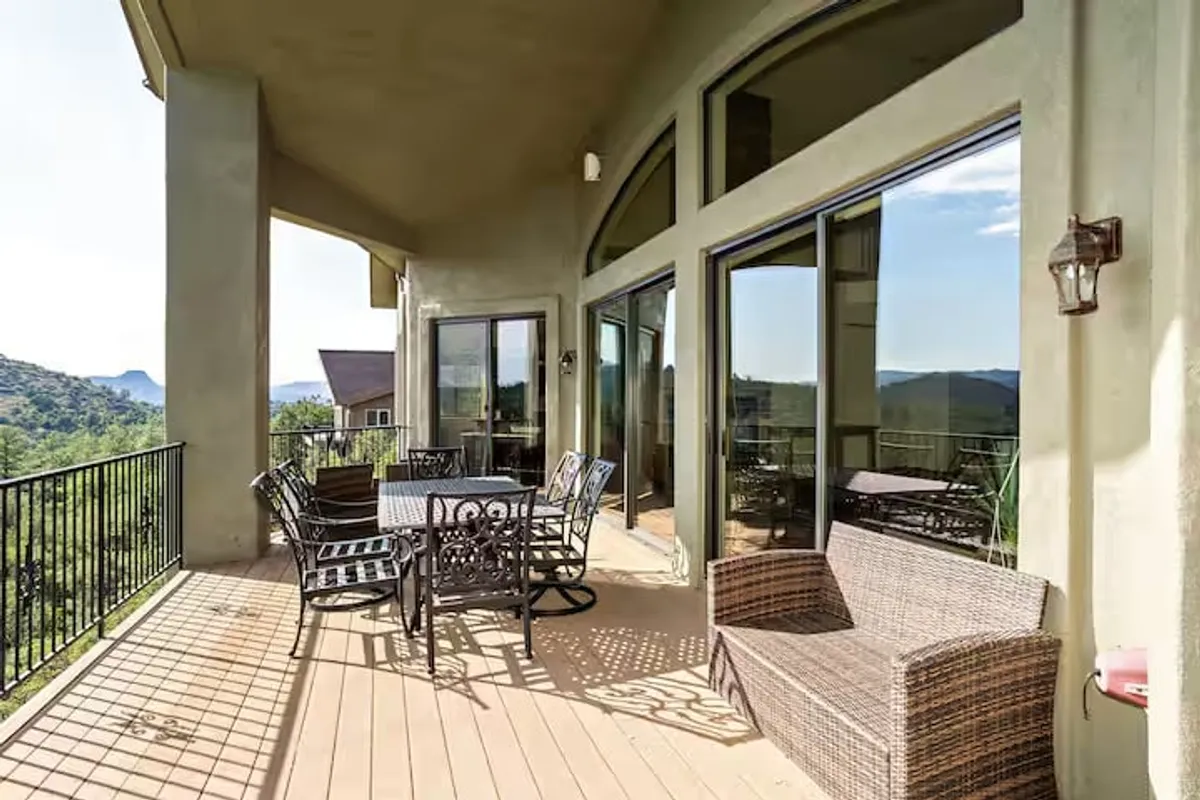An inviting exterior patio is set with outdoor furniture, overlooking a stunning mountain view through large windows. This tranquil space is ideal for relaxing after a round of golf or gathering with friends to recap the day's highlights.
