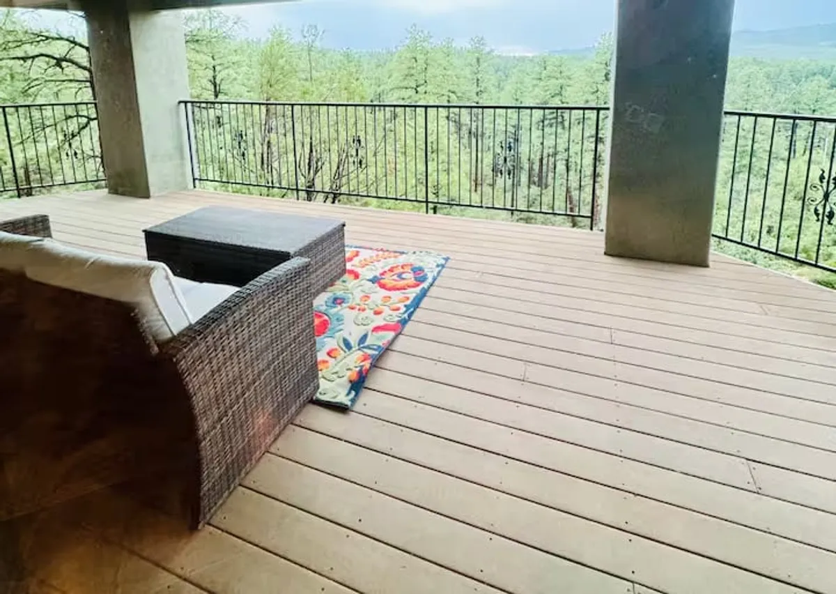 Wicker seating and a decorative rug create a comfortable, inviting outdoor lounge area with a scenic view. The setup is ideal for relaxing, gathering with friends, or enjoying drinks while taking in the natural surroundings.