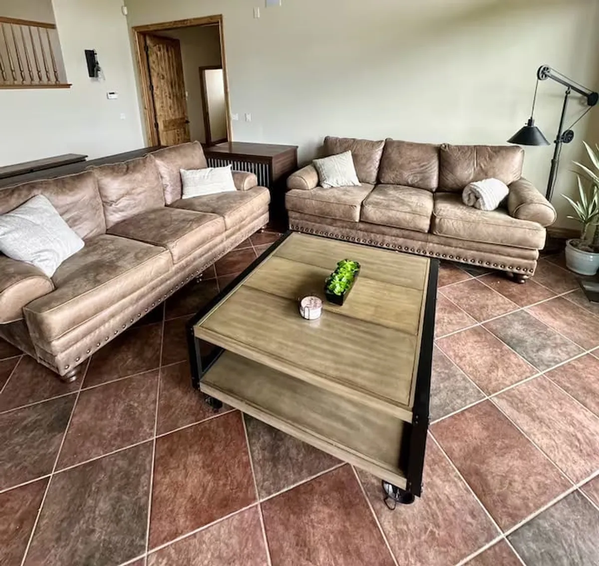 A cozy interior lounge with leather sofas, a coffee table, and a decorative plant, inviting relaxation and conversation. The space is arranged for comfort and group interaction, ideal for board games and after-adventure unwinding.